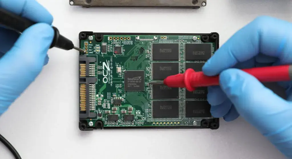 Technician testing an open SSD circuit board with probes.